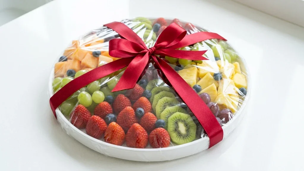 A nicely packaged fruit platter ready for delivery to a hospital ward, emphasizing hygiene and aesthetics. מגשי פירות טריים עד בית החולים בילינסון